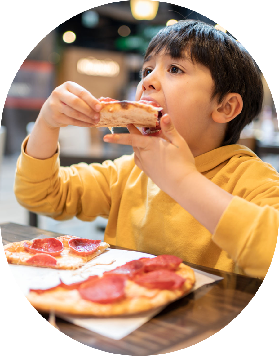 Child eating pepperoni pizza in cafe.