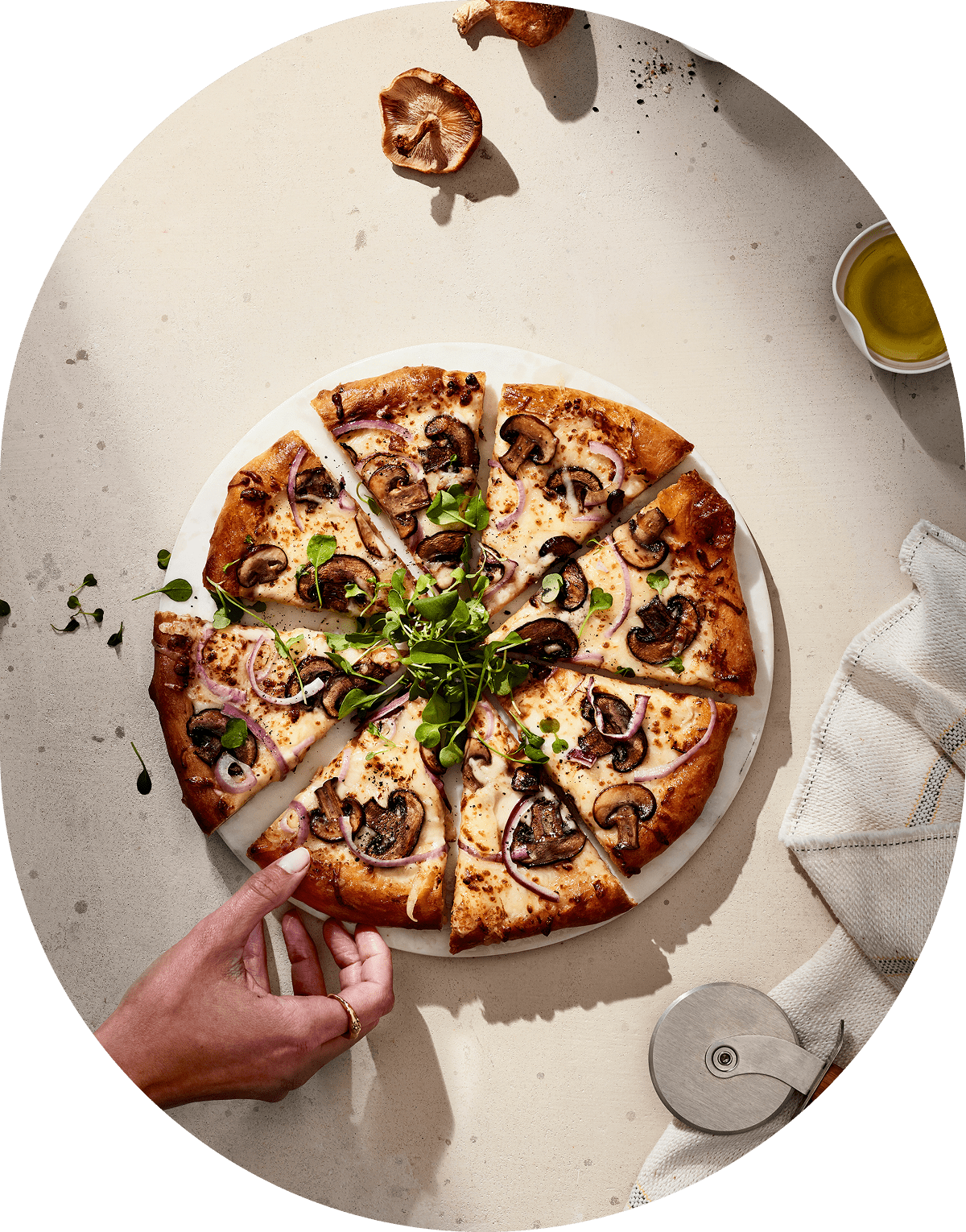Hand reaching for sliced mushroom pizza.